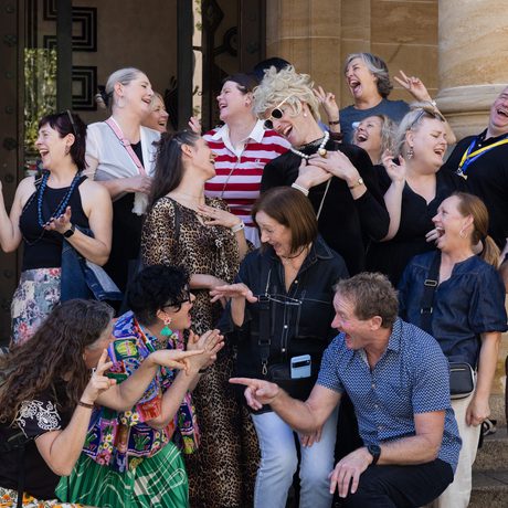 A group of people smiling and laughing outside an entrance.