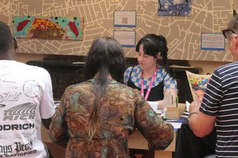 Picture of a group of people sat at a table, with a map background