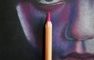 Pencil drawing of a face in shades of reds and purples with a pink pencil on top