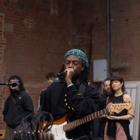 Bundy performing with microphone and guitar.
