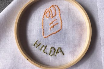 Stitching and embroidery on a white cloth of a item and name.