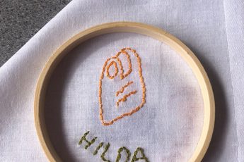 Stitching and embroidery on a white cloth of a item and name.