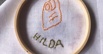 Stitching and embroidery on a white cloth of a item and name.