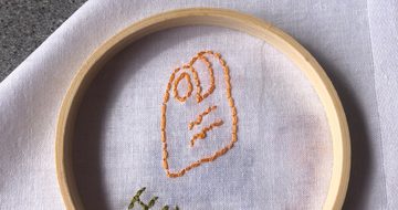 Stitching and embroidery on a white cloth of a item and name.