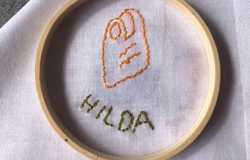 Stitching and embroidery on a white cloth of a item and name.