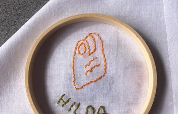 Stitching and embroidery on a white cloth of a item and name.