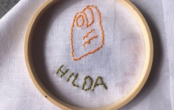 Stitching and embroidery on a white cloth of a item and name.