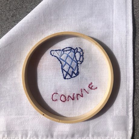 Stitching and embroidery on a white cloth of a item and name.