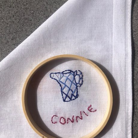 Stitching and embroidery on a white cloth of a item and name.