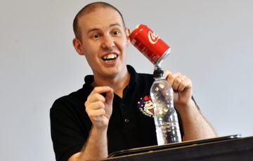 A person balancing a can of pop on top of a water bottle.