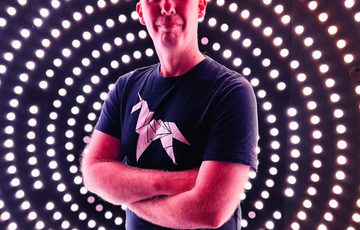 A person in the centre of black background with white dots around.
