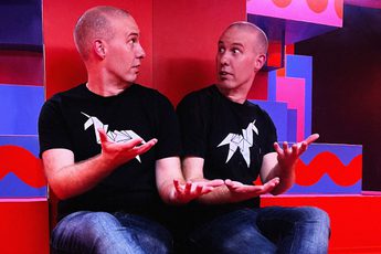 A person sitting on coloured steps looking at themselves in a large mirror.