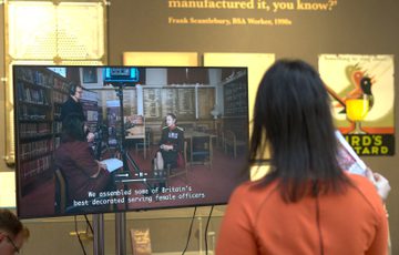 A person standing in front of a TV screen in a gallery setting.