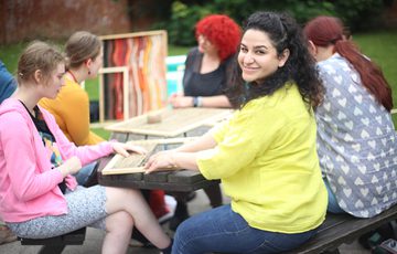 A group of people who are seated at a table the artist is looking to the camera and smiling.