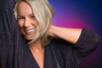 A person with their hands by their head and smiling.