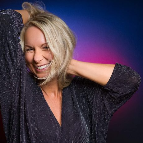 A person with their hands by their head and smiling.