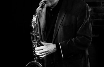 A black and white portrait of a person playing the saxophone.