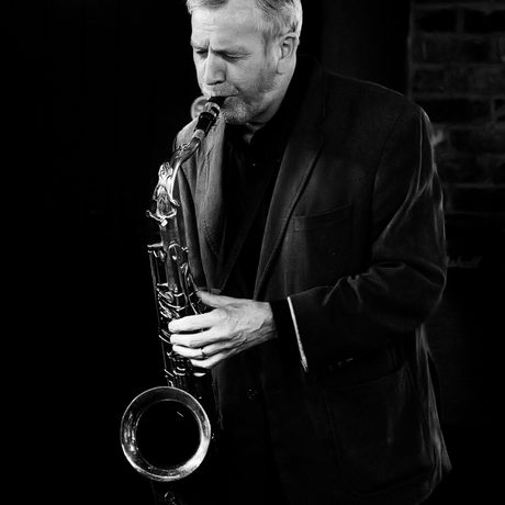 A black and white portrait of a person playing the saxophone.