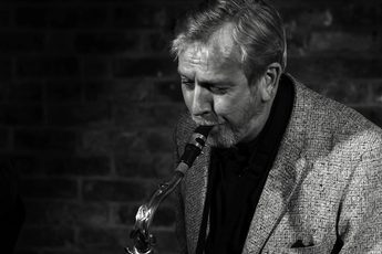 A black and white portrait of a person playing the saxophone.