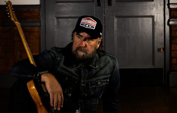 Brad Henshaw sitting with his guitar.