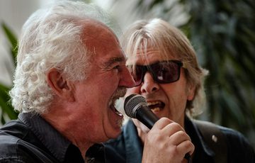 Close up of a two people singing into a microphone.