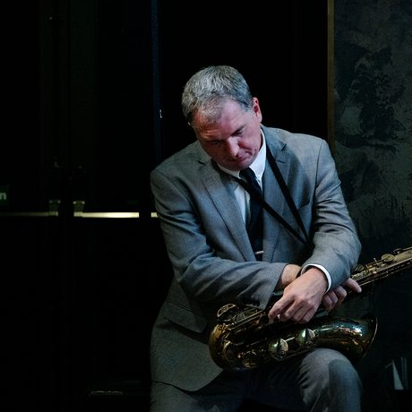 A person sitting with a saxophone on their lap.