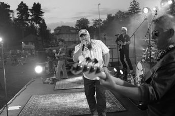 A black and white photo of a band on stage with a person singing in the centre.