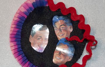 A craft item made of three faces on a dark circular craft item.