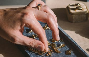 A hand reaching to select a jewellery price from a try of jewellery.