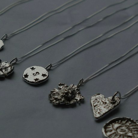 A selection of grey necklaces on a grey background.