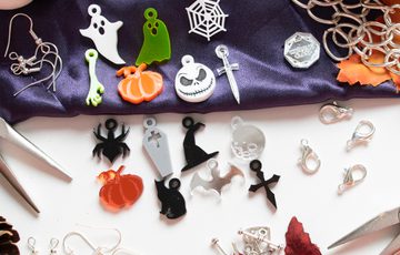 Halloween themed jewellery making materials laid out featuring ghosts, pumpkins, spiders.