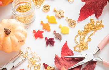 Jewellery making materials, laid out featuring autumn leaves and tools surrounded by leaves and pumpkins.