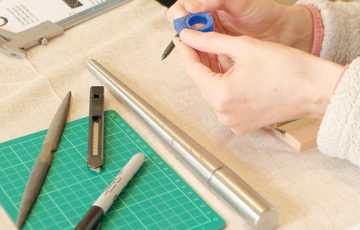 Jewellery making equipment and pens on a table.