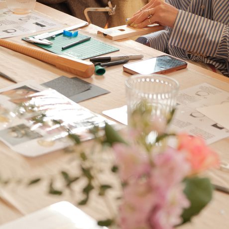 People sitting making jewellery with equipment in front of them on a table.
