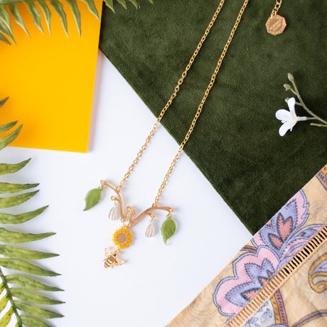 A necklace designed with leaves at the either end, and a sunflower and bee in the centre.