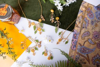 A jewellery set comprising of bracelet, two necklaces and two sets of earrings, all designed with leaves, sunflowers and bees.