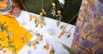A jewellery set comprising of bracelet, two necklaces and two sets of earrings, all designed with leaves, sunflowers and bees.