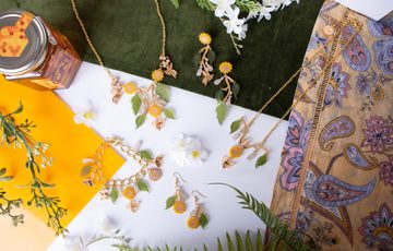 A jewellery set comprising of bracelet, two necklaces and two sets of earrings, all designed with leaves, sunflowers and bees.