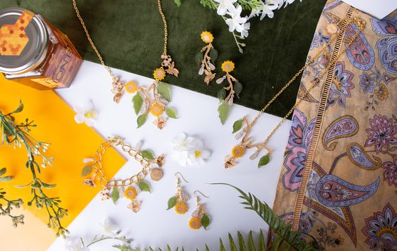 A jewellery set comprising of bracelet, two necklaces and two sets of earrings, all designed with leaves, sunflowers and bees.