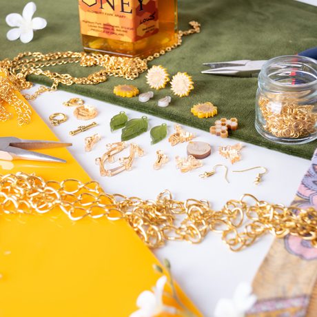 Jewellery making equipment and materials, featuring leaves, sunflowers and bees. A honey pot is in the background.