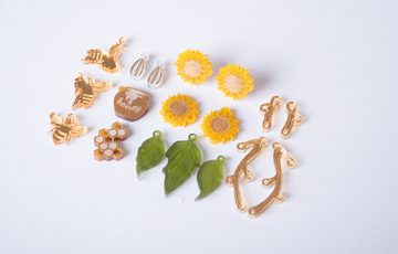 Jewellery making materials, laid out featuring leaves, sunflowers and bees.