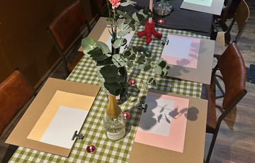 A table set up with drawing supplies and flowers in vases.