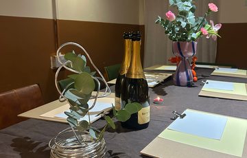 A table set up with drawing supplies, flowers, and bottles of wine.