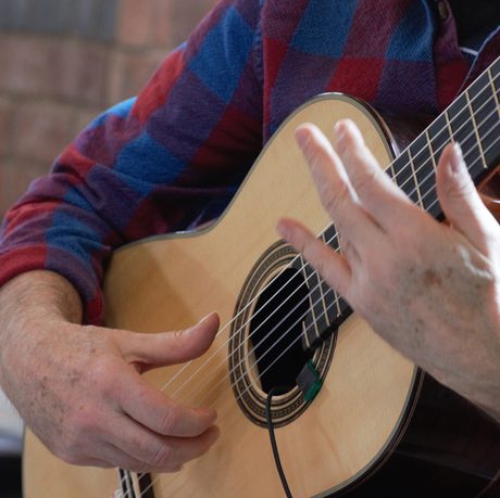 Close up of hands playing a guitar.