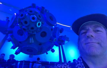 A perpson with circular abstract piece behind lit with blue light.