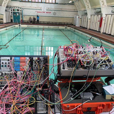A collection of equipment with colourful wires in front of a swimming pool.