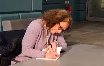 A person sitting at a desk signing a book.