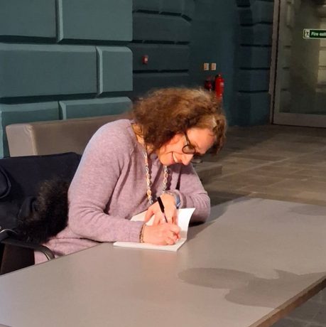 A person sitting at a desk signing a book.