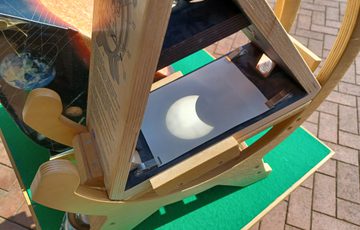 Wooden solar viewer projecting a partial solar eclipse onto a screen