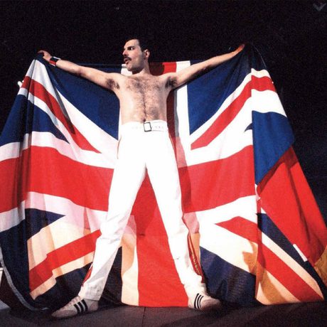 Picture of a man in white trousers holding a Union flag behind him